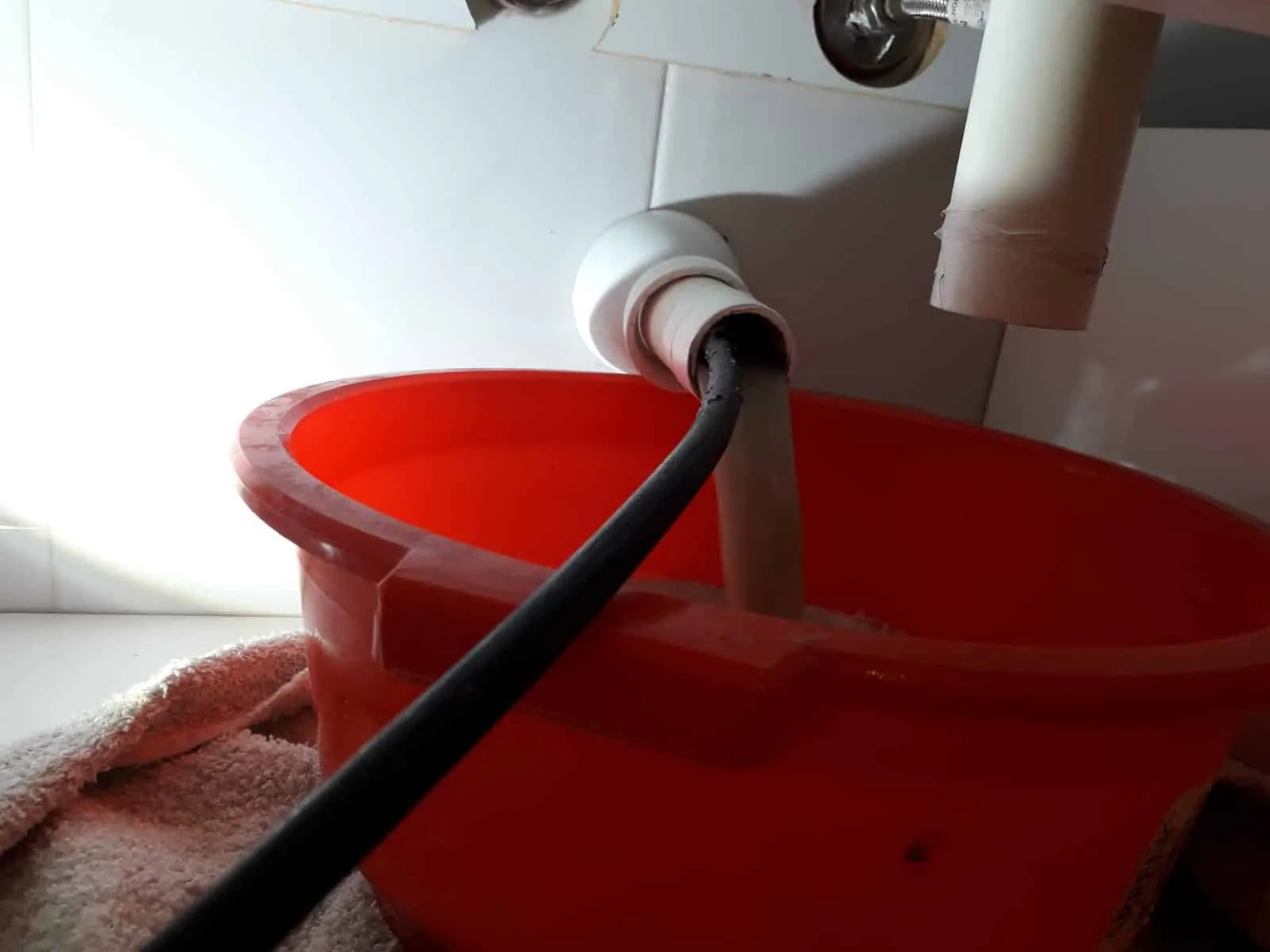 Desatasco manual de un sifón con manguera bajo el fregadero