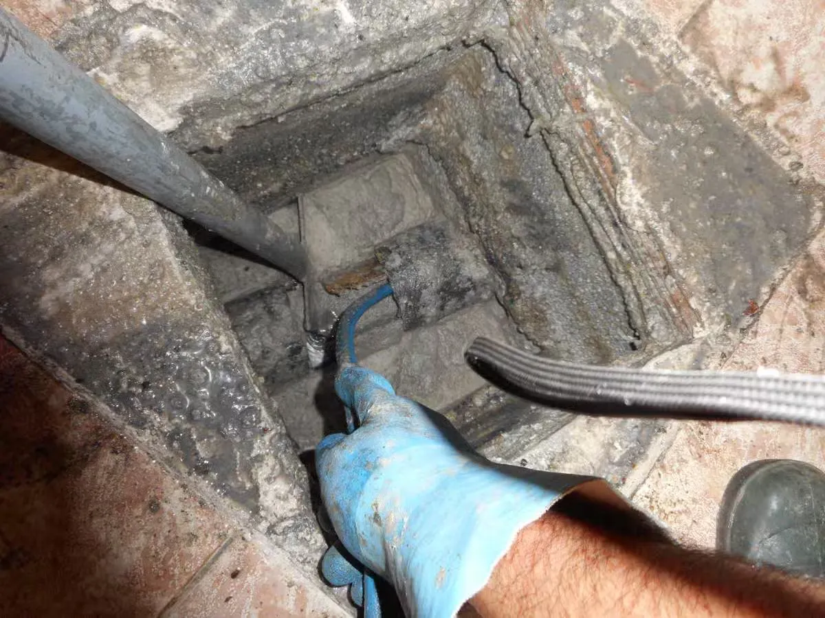 Técnico de Tuberías y Aljibes trabajando con manguera de alta presión en una arqueta en Mallorca