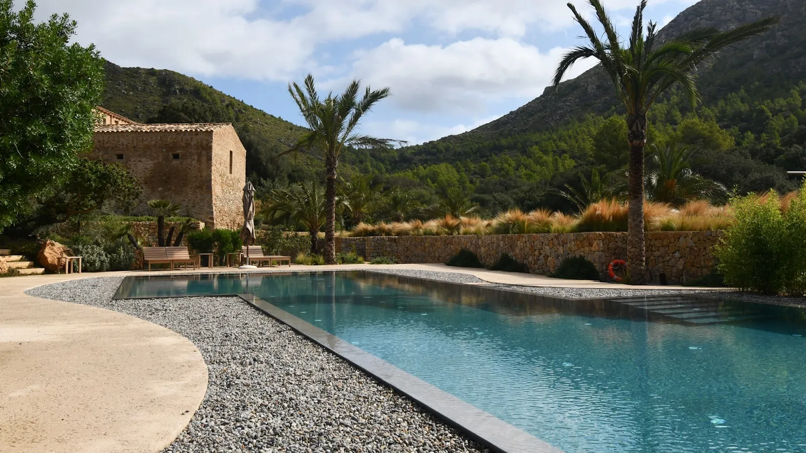 Villa mallorquina de piedra con piscina y palmeras al pie de la montaña